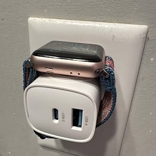 Watch held on the magnetic charging surface at a wall outlet